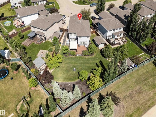 Spacious backyard featuring a manicured lawn, multi-level wooden deck, and mature landscaping - 18 Voleta Crest, Spruce Grove, AB 