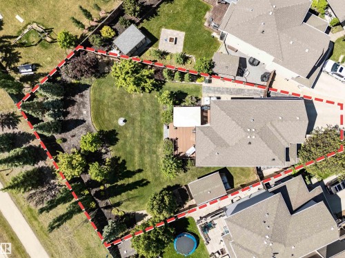 Expansive property featuring a well-maintained lawn, mature trees, a private wooden deck, and a detached shed - 18 Voleta Crest, Spruce Grove, AB 