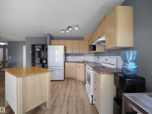 Kitchen featuring light wood-finish cabinetry, a freestanding range, and a dual-basin sink - #217 240 Spruce Ridge Rd, Spruce Grove, AB - Indoor Photo Showing Kitchen