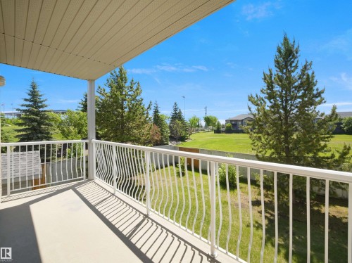 Spacious outdoor balcony with a light-colored concrete surface, white metal railing, and a slatted soffit ceiling - #217 240 Spruce Ridge Rd, Spruce Grove, AB - Outdoor With Balcony With Exterior
