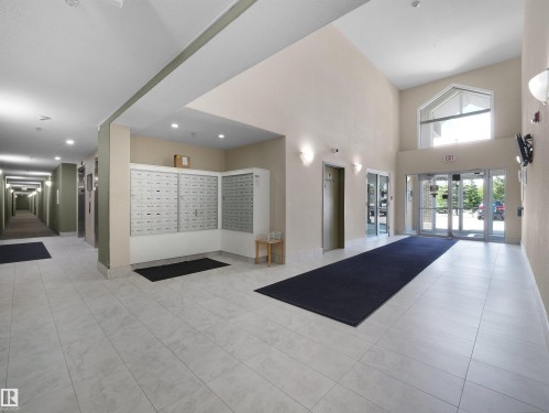 Spacious lobby featuring high ceilings, large windows, tile flooring, and integrated mailboxes - #217 240 Spruce Ridge Rd, Spruce Grove, AB - Indoor Photo Showing Other Room