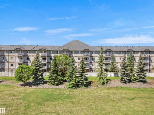 Multi-story building featuring numerous private balconies, a pitched shingle roof, and a beige exterior facade - #217 240 Spruce Ridge Rd, Spruce Grove, AB - Outdoor With Balcony