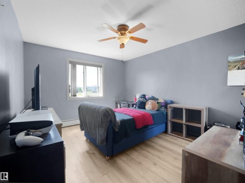 Bedroom featuring light wood-finish flooring, a ceiling fan with integrated lighting, and a single window with white trim - #217 240 Spruce Ridge Rd, Spruce Grove, AB - Indoor Photo Showing Bedroom