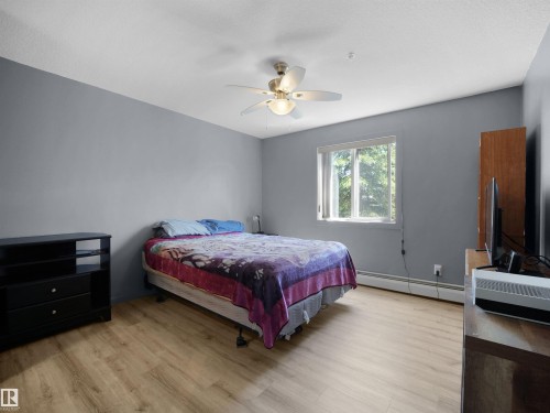 Bedroom featuring wood-finish flooring, a ceiling fan with integrated lighting, and a window with a white frame - #217 240 Spruce Ridge Rd, Spruce Grove, AB - Indoor Photo Showing Bedroom
