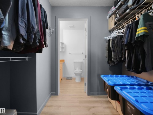 Walk-through closet featuring wood-finish flooring, wire shelving, and neutral wall tones - #217 240 Spruce Ridge Rd, Spruce Grove, AB - Indoor With Storage