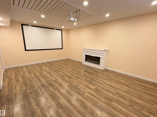 Spacious room featuring wood-finish flooring, a wall-mounted projector screen, and a ceiling-mounted projector - 21354 87A Avenue, Edmonton, AB 
