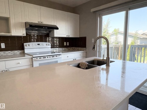 Kitchen island featuring a built-in stainless steel double-basin sink and a gooseneck faucet - 21354 87A Avenue, Edmonton, AB 