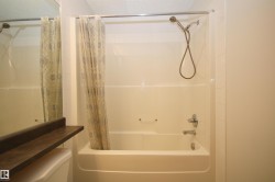 Alcove bathtub and shower combination featuring a curved shower rod, chrome fixtures, and a handheld showerhead - 