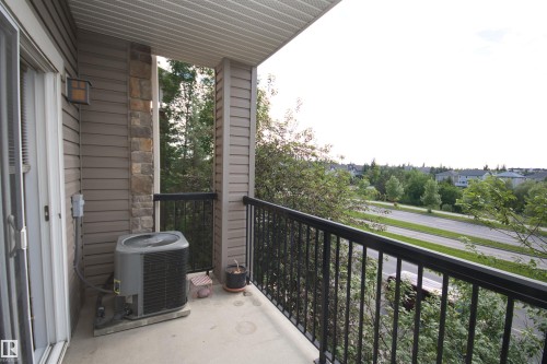 Private balcony featuring a sliding glass door entry, durable concrete flooring, and a black metal railing - 311 2098 Blackmud Creek Drive, Edmonton, AB 