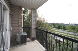 Private balcony featuring a sliding glass door entry, durable concrete flooring, and a black metal railing - 