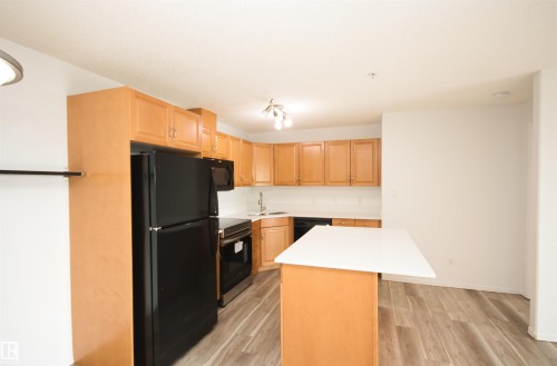Kitchen featuring light wood cabinetry, white subway tile backsplash, and a black appliance suite including a refrigerator, microwave, and oven - 311 2098 Blackmud Creek Drive, Edmonton, AB 