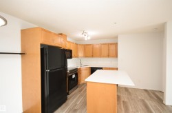 Kitchen featuring light wood cabinetry, white subway tile backsplash, and a black appliance suite including a refrigerator, microwave, and oven - 
