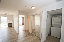 Light wood-finish flooring throughout, featuring a fireplace with white mantel, sliding glass door, mirrored closet doors, and built-in laundry appliances - 