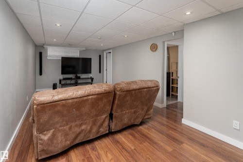 Finished room featuring wood-finish flooring, recessed lighting, drop ceiling, and light gray walls - 10008 144 Ave, Edmonton, AB 