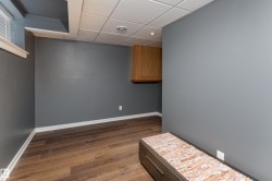 Spacious room featuring wood-finish flooring, dark gray painted walls, and white baseboards - 