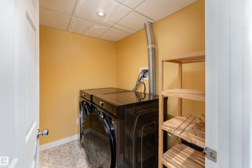 Laundry area featuring patterned tile flooring, a drop ceiling with recessed lighting, and a wooden shelving unit - 10008 144 Ave, Edmonton, AB 