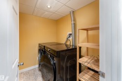Laundry area featuring patterned tile flooring, a drop ceiling with recessed lighting, and a wooden shelving unit - 