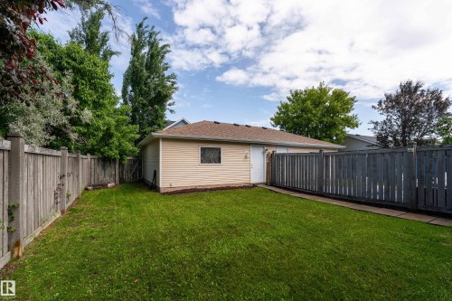 Detached garage featuring horizontal siding, a side door, and a single window with grilles - 10008 144 Ave, Edmonton, AB 