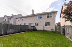 Private backyard featuring a wooden fence, manicured lawn, and a small deck with steps leading to the back entrance - 