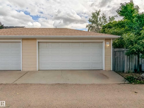 Two-car garage with white panel doors and light-colored siding - 10008 144 Ave, Edmonton, AB 