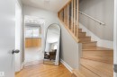 Hardwood flooring in entry with natural wood staircase featuring a banister and spindles - 10008 144 Ave, Edmonton, AB 