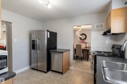 Kitchen featuring stainless steel appliances, wood-finish cabinetry, tile flooring, subway tile backsplash, and a double basin sink - 