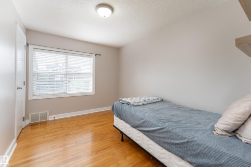 Bright room featuring wood-finish flooring, a white window frame, and a white interior door - 10008 144 Ave, Edmonton, AB 