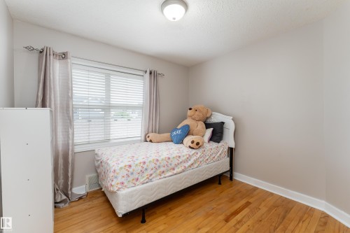 Room featuring wood-finish flooring, neutral wall paint, and a window with blinds - 10008 144 Ave, Edmonton, AB 