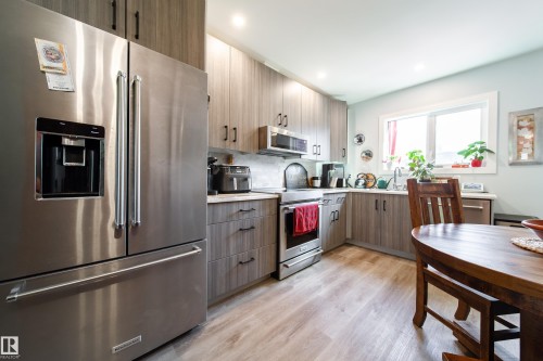 Modern kitchen featuring stainless steel appliances, wood-finish cabinetry, and light countertops - 10811 73 Avenue, Edmonton, AB 