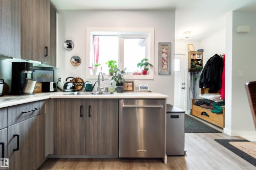 Kitchen featuring wood-finish cabinetry, light-toned countertops, and a stainless steel dishwasher - 10811 73 Avenue, Edmonton, AB 