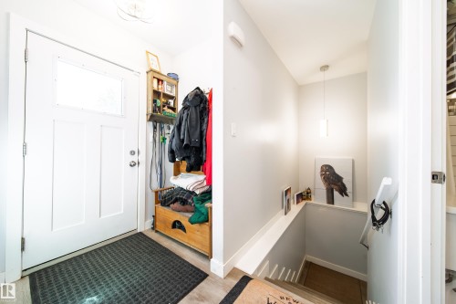 Entryway featuring a white paneled door with a frosted transom window, wood-finish flooring, and light gray wall paint - 10811 73 Avenue, Edmonton, AB 