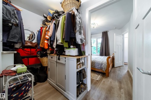 Walk-in closet featuring wood-finish flooring and a built-in storage island with a light-toned countertop - 10811 73 Avenue, Edmonton, AB 