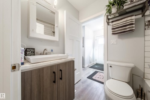 Bathroom featuring a floating wood-finish vanity with a rectangular vessel sink and a wall-mounted medicine cabinet - 10811 73 Avenue, Edmonton, AB 