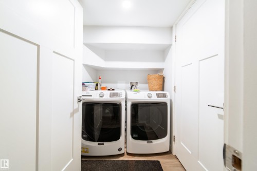 Dedicated laundry area featuring a built-in shelf, white shaker-style doors, and light-toned flooring - 10811 73 Avenue, Edmonton, AB 