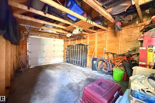 Single-car garage featuring a paneled overhead door, exposed wood beam ceiling, and wood-paneled walls - 10811 73 Avenue, Edmonton, AB 
