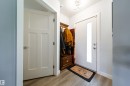 Entryway featuring wood-finish flooring, a white paneled interior door with a brushed nickel lever, and a white front door with a vertical glass insert - 10811 73 Avenue, Edmonton, AB 