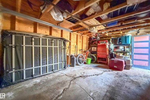 Attached garage interior featuring wood-paneled walls and exposed ceiling joists - 10811 73 Avenue, Edmonton, AB 