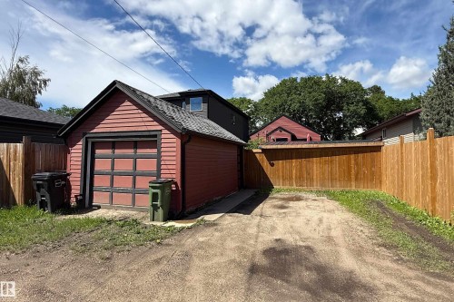 Detached single-car garage with red siding and a black paneled garage door - 10811 73 Avenue, Edmonton, AB 