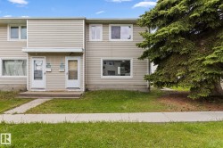 Duplex exterior with light-colored siding and white trim windows - 