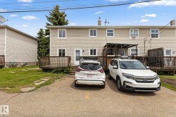 Rear exterior featuring tan horizontal siding, multiple windows, and a wood-decked patio with railings - 