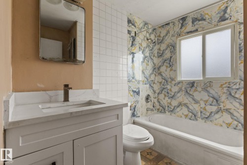 Bathroom featuring a white vanity with an integrated sink, a contemporary faucet, and a wall-mounted mirror - 110 12988 122B Avenue, Edmonton, AB 
