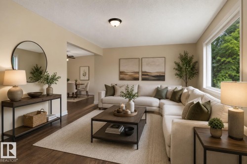 Bright living area featuring wood-finish flooring, a contemporary ceiling light fixture, and a large picture window - #110 12988 122B Av Nw, Edmonton, AB - Indoor Photo Showing Living Room