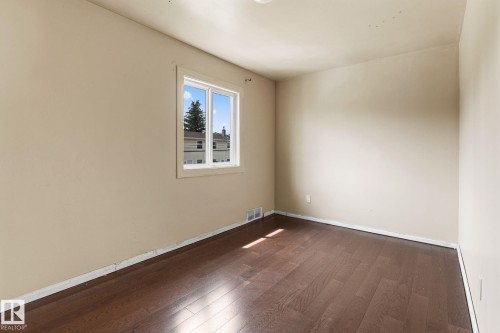 Room featuring wood-finish flooring, a double-paned window, and neutral wall tones - 110 12988 122B Avenue, Edmonton, AB 