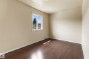 Room featuring wood-finish flooring, a double-paned window, and neutral wall tones - 110 12988 122B Avenue, Edmonton, AB 