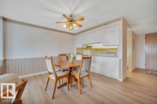 Open-concept dining area featuring wood-finish flooring, a ceiling fan with integrated lighting, and a breakfast bar with white cabinetry - 316 2011 137 Avenue, Edmonton, AB - Indoor Photo Showing Dining Room
