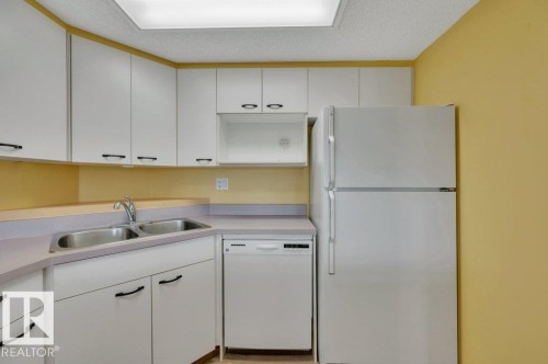 Kitchen featuring white cabinetry, a double basin stainless steel sink, white dishwasher, and white refrigerator - 316 2011 137 Avenue, Edmonton, AB - Indoor Photo Showing Kitchen With Double Sink