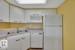 Kitchen featuring white cabinetry, a double basin stainless steel sink, white dishwasher, and white refrigerator - 