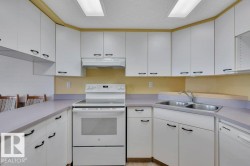 Kitchen featuring white cabinetry with black hardware, a stainless steel double sink, a white electric range, and integrated dishwasher - 