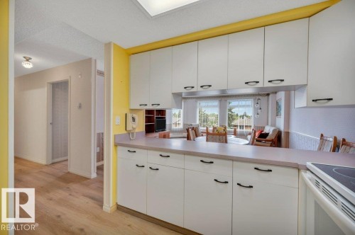 Bright kitchen featuring white cabinetry with black hardware, a light-toned countertop, and a built-in cooktop - 316 2011 137 Avenue, Edmonton, AB - Indoor Photo Showing Kitchen