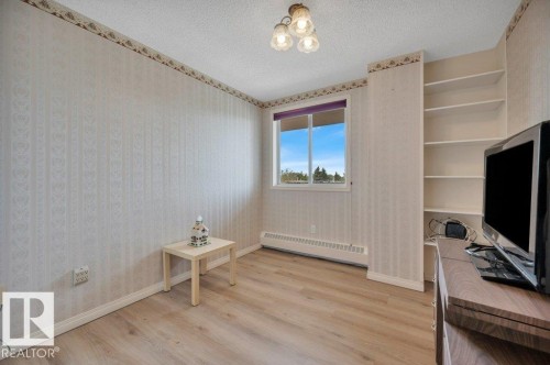 Room featuring wood-finish flooring, built-in shelving, a window with outdoor scenery, and a ceiling-mounted light fixture - 316 2011 137 Avenue, Edmonton, AB - Indoor